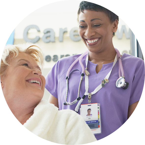 Nurse smiling at older woman seated in wheelchair