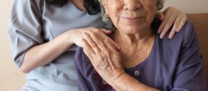 caregiver's hand on elderly patient's shoulder