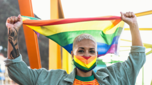 person wearing pride mask and holding pride flag