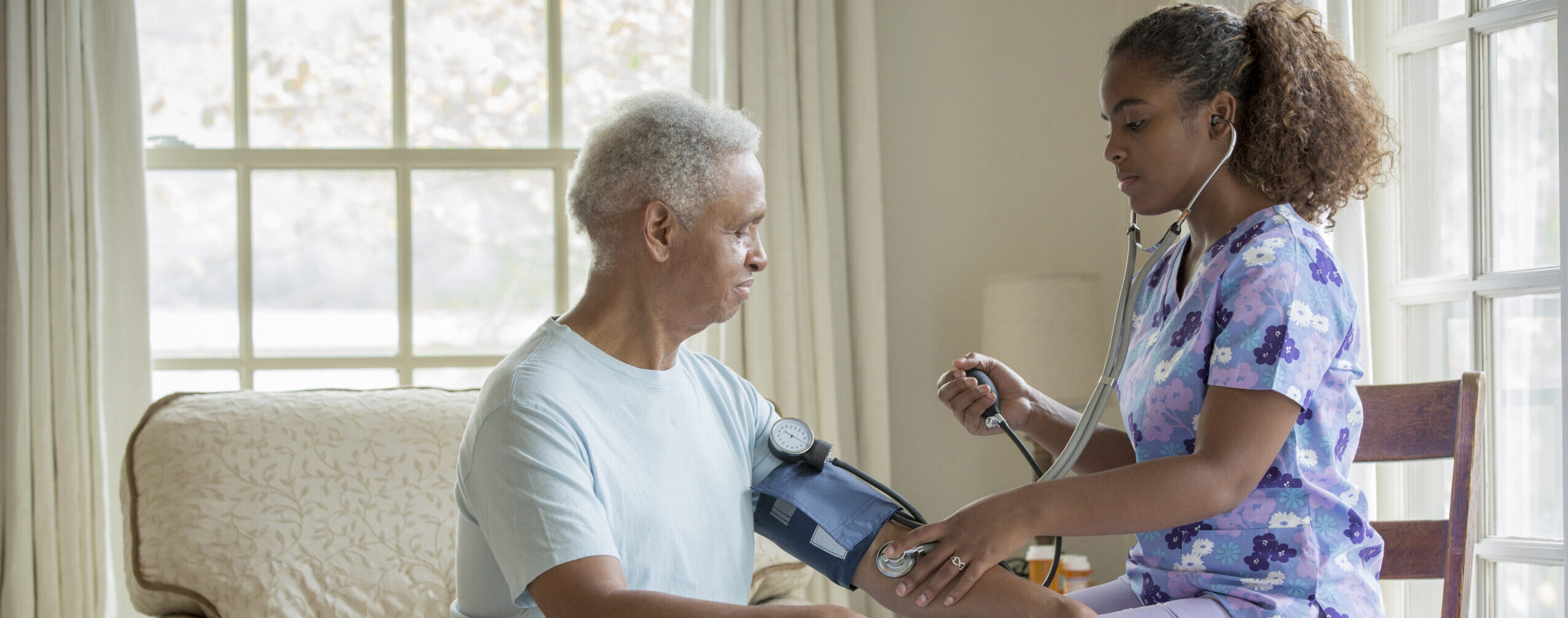 Nurse taking patient's blood pressure at their home