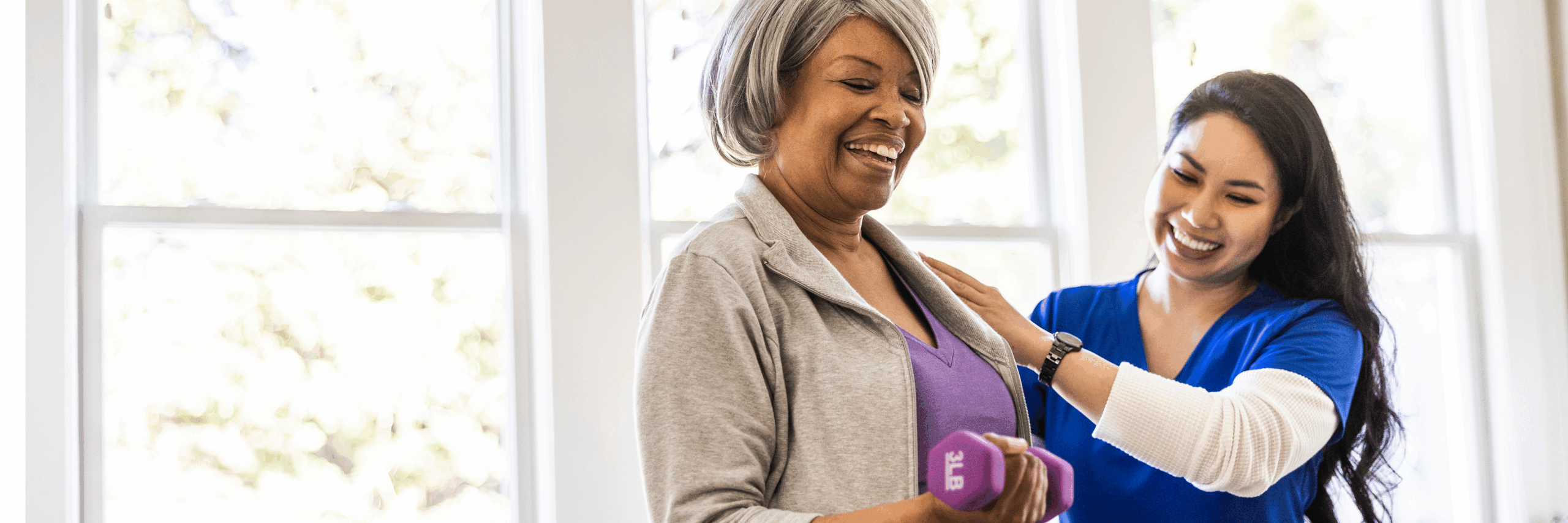 Home Health nurse helping patient lift weights in the comfort of her home